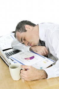 Businessman asleep at his desk on white background